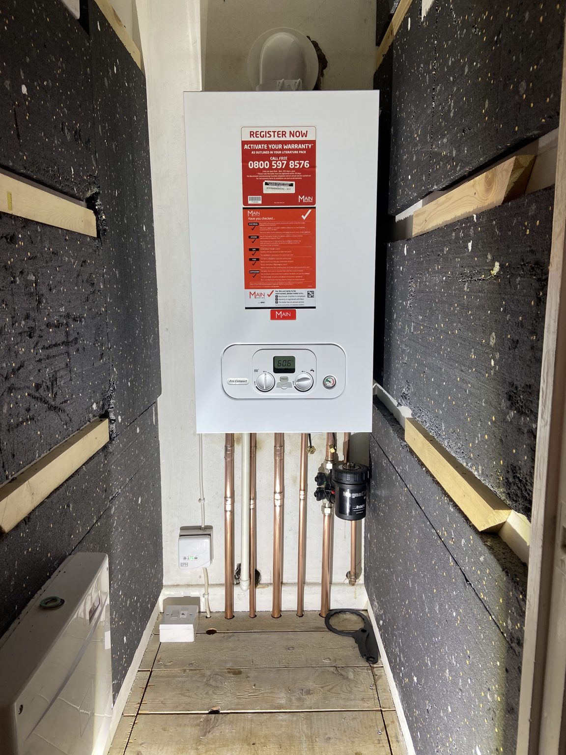 A new boiler mounted in a boxed-in space with insulated walls and copper pipework