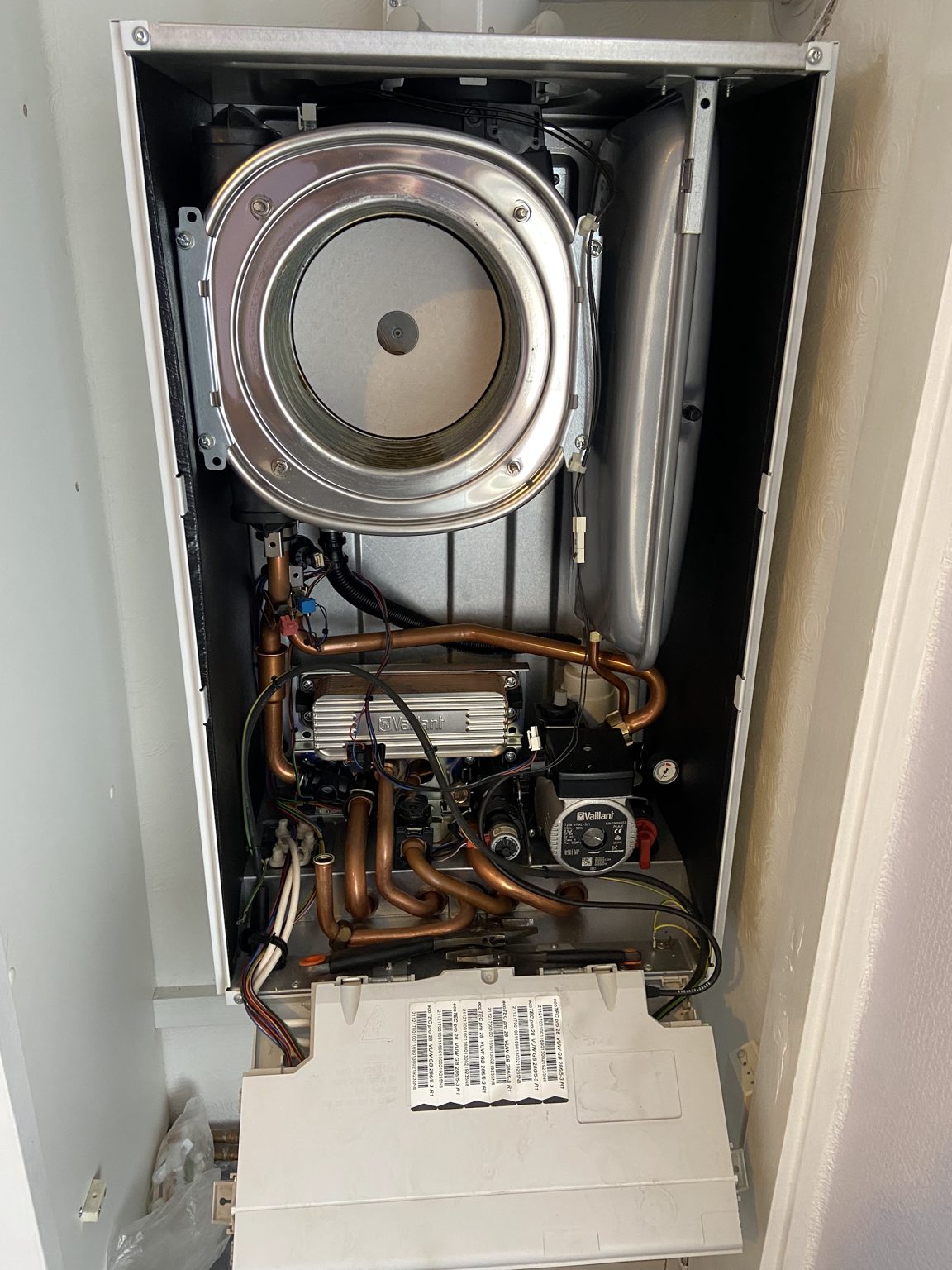 A boiler with its casing removed, showing the burner and internal pipework during a repair
