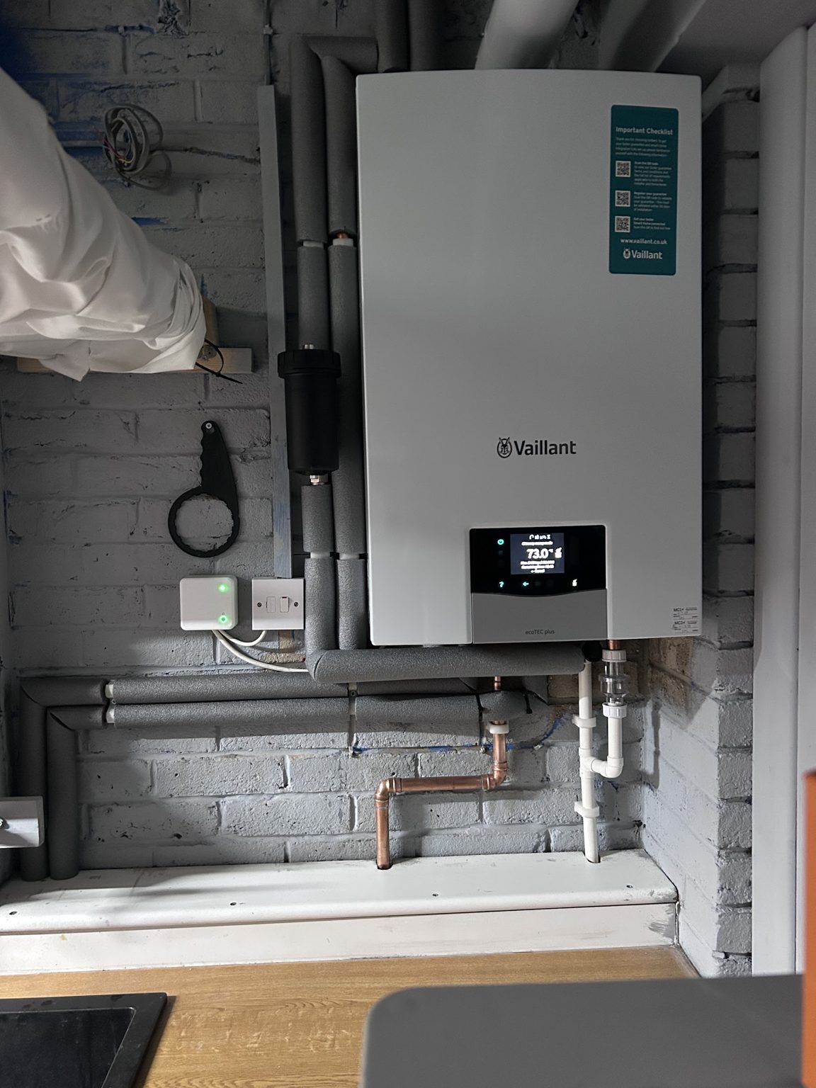 A Vaillant boiler installed on a painted brick wall in a garage