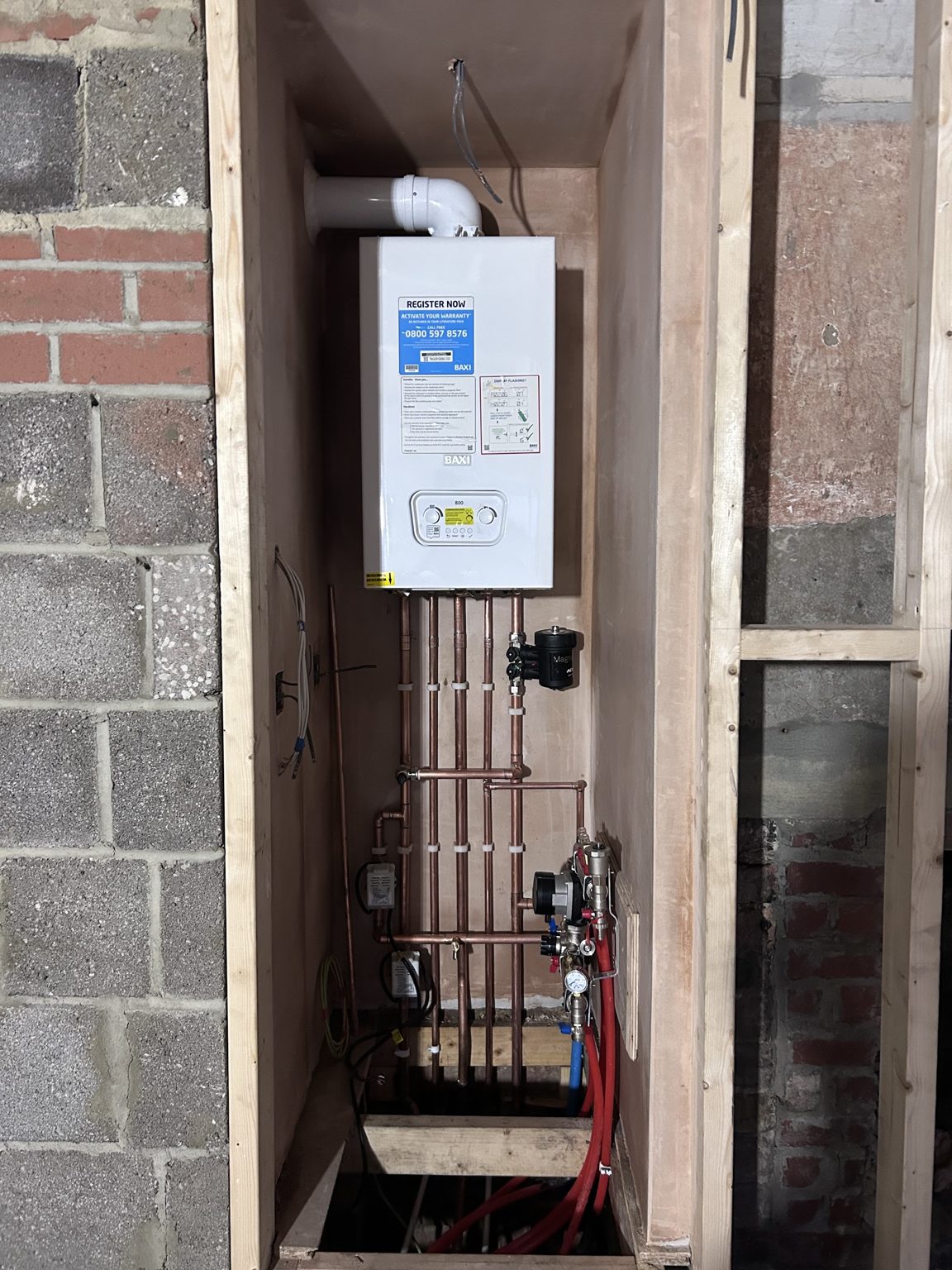 A new boiler fitted inside fresh timber framing with the pipework below
